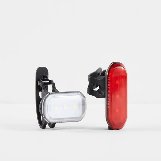 A set of two bicycle lights, one with a red flare and the other with a black, round LED light, both mounted on a black adjustable strap.
